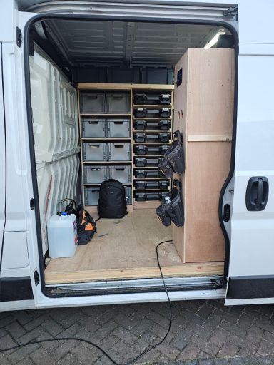 Interior of a van with storage shelves, boxes, and equipment neatly organized.